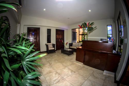a lobby with a desk and chairs and plants at Hotel Iguana Verde in Orotina