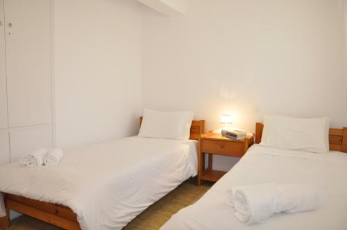 a room with two beds with white sheets and a table at Ava Apartments in Agios Gordios