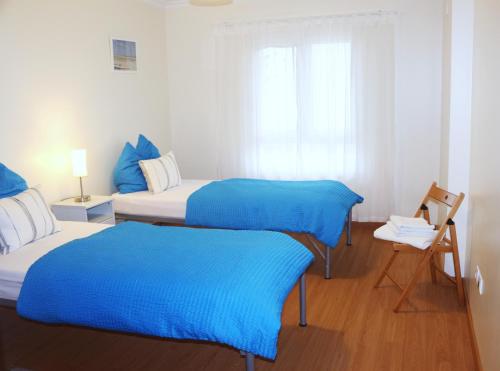 バレアルにあるBaleal Beach Apartmentの青いシーツと椅子が備わるベッド2台付きの客室です。