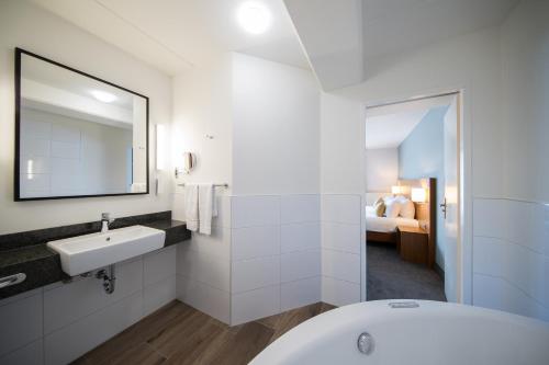 a bathroom with a sink and a bath tub at Bilderberg Résidence Groot Heideborgh in Garderen