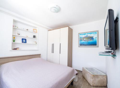 a bedroom with a bed and a flat screen tv at Apartments Laura in Korčula