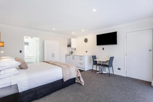 a bedroom with a bed and a desk and a kitchen at Superior Dunedin Apartments in Dunedin