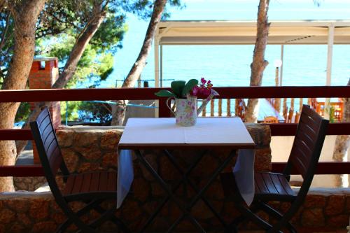 a table with two chairs and a vase of flowers at Pension Tamaris in Sveta Nedelja