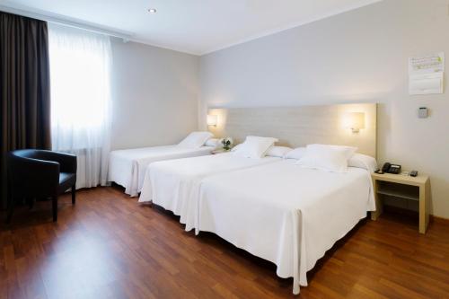 a hotel room with two beds and a chair at Hotel Valencia in Ferrol