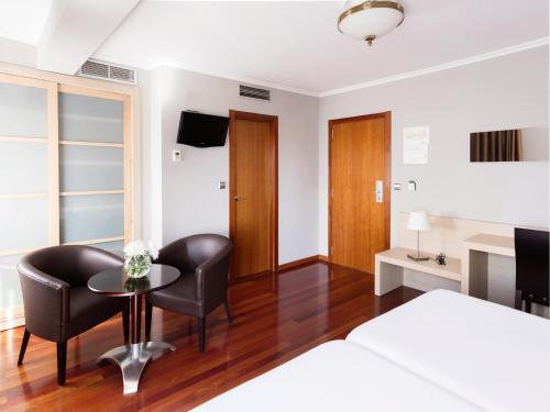 a bedroom with a bed and a table and chairs at Hotel Valencia in Ferrol