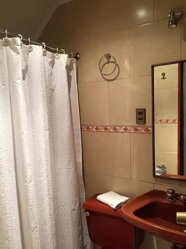a bathroom with a white shower curtain and a sink at Hostería Bilbao in Villarrica