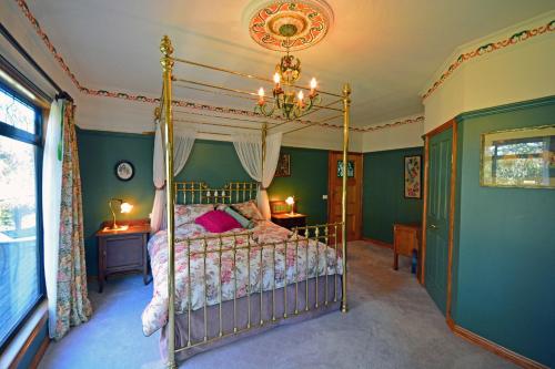 um quarto com uma cama de dossel e paredes verdes em Araluen Park Cottages em Lakes Entrance