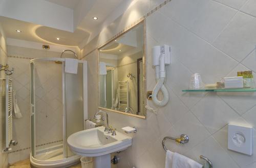 a white bathroom with a sink and a shower at Hotel Verdemare in Marina di Pietrasanta