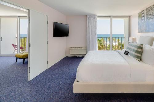 a white bedroom with a large bed and a balcony at Plunge Beach Resort in Fort Lauderdale