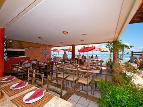 een restaurant met tafels en stoelen en uitzicht op de oceaan bij Sonia Flats Pipa's Bay - Flat 211 in Pipa