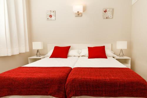 プエルト・デル・カルメンにあるBonito Apartamento & Piscinaのベッドルーム1室(大型ベッド1台、赤い枕付)