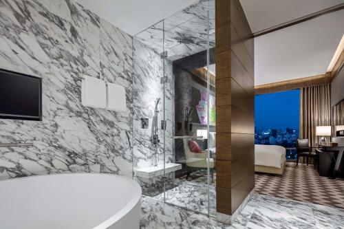 a bathroom with a tub and a tv and a bedroom at 137 Pillars Suites Bangkok in Bangkok