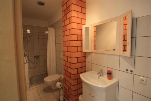 a bathroom with a white sink and a brick wall at Pension vorm Darß in Hirschburg