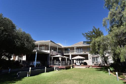 a large white building with umbrellas in front of it at Tredenham Boutique Hotel in Bloemfontein