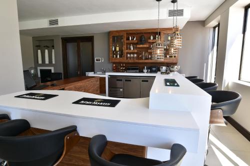 a kitchen with a white counter and black chairs at Tredenham Boutique Hotel in Bloemfontein