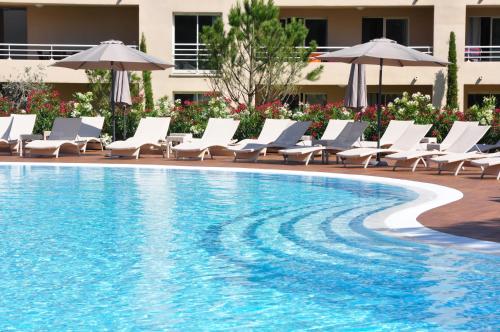 a swimming pool with lounge chairs and umbrellas at Résidence Salina Bay in Porto-Vecchio