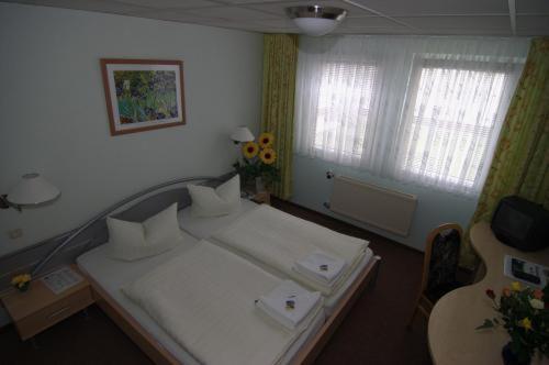 Zimmer mit einem weißen Bett und einer Gitarre in der Unterkunft Waldhotel Seelow in Seelow