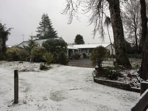 a yard covered in snow with a house in the background at Tongariro Crossing Lodge in National Park