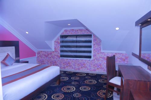a bedroom with a bed and a desk and a window at Galaxy Grand Hotel in Nuwara Eliya