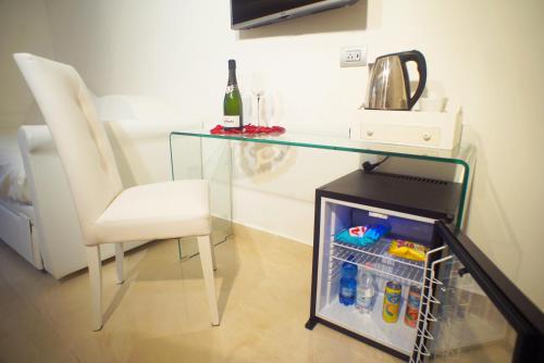 a glass table and a chair next to a refrigerator at San Pietro Grand Suite in Rome