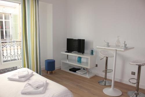 une chambre blanche avec un lit et une télévision dans l'établissement Eve, à Cannes