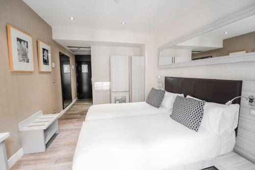 een slaapkamer met een groot wit bed met kussens bij Petit Palace Puerta del Sol in Madrid