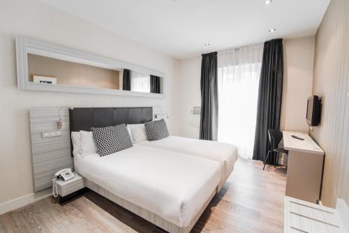 a bedroom with a large white bed and a television at Petit Palace Puerta del Sol in Madrid
