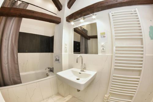 a white bathroom with a sink and a bath tub at Hostel HOMEr - Old Town Square in Prague