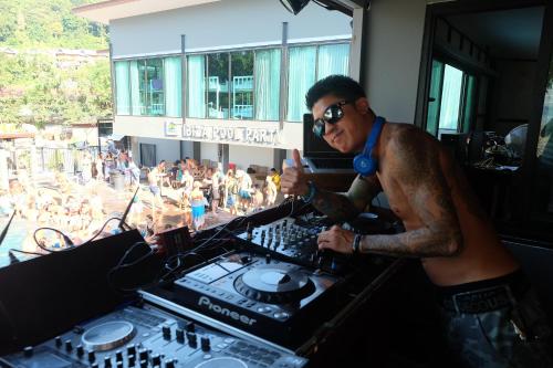 a man with a tattoo sitting at a mixing console at Ibiza House Phi Phi in Phi Phi Don