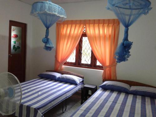 zwei Betten in einem Zimmer mit Fenster in der Unterkunft Didula Holiday Resort in Anuradhapura