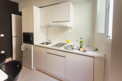 a white kitchen with a sink and a refrigerator at Sevilla Centro Casa Del Pop in Seville