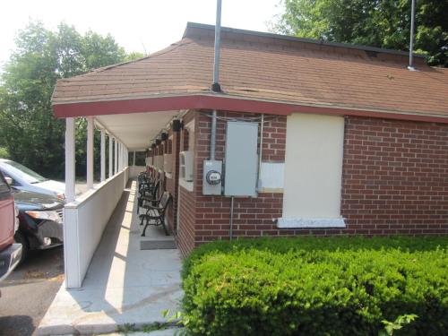 a small brick house with a porch and chairs at Pinecrest Motel in Clinton