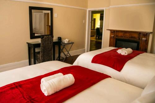 2 Betten in einem rot-weißen Zimmer in der Unterkunft Guesthouse@Mbalistar in Queenstown