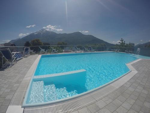 una piscina blu con montagne sullo sfondo di Camping Villaggio Paradiso a Domaso