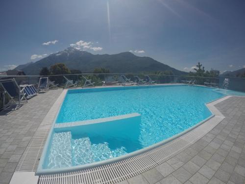ein blauer Pool mit Bergen im Hintergrund in der Unterkunft Camping Villaggio Paradiso in Domaso