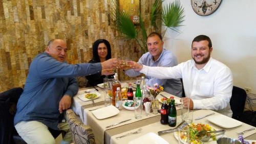 un gruppo di persone sedute attorno a un tavolo che bevono bicchieri di Kolhida Complex a Elkhovo