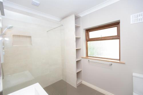 baño blanco con ducha y ventana en Luskin's en Cong