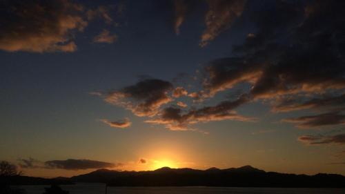 a sunset with the sun setting behind some mountains at Marriner's Boutique Guesthouses in Rawene