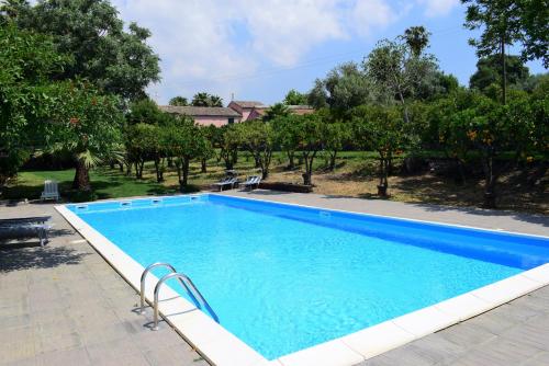 una grande piscina blu in un cortile alberato di Terre del Cardinale Country Suites a Catania