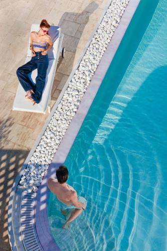 a man sitting on a boat next to a swimming pool at Above Blue Suites in Imerovigli