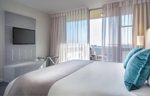 a bedroom with a large bed and a large window at Lagoon Beach Hotel & Spa in Cape Town