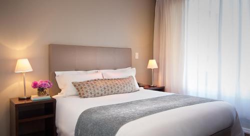 a bedroom with a large bed and two lamps at Lagoon Beach Hotel & Spa in Cape Town
