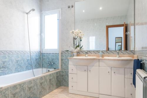 Un baño con dos lavabos, una bañera y un espejo. en Villa Med, en Sitges