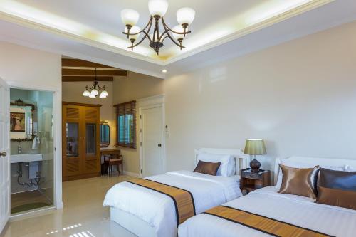 a bedroom with two beds and a bathroom at The Lek Aree in Bangkok