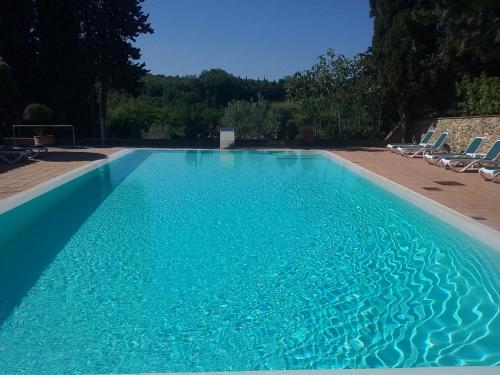 a swimming pool with chairs and blue water at Hotel Pescille Country House - Tuscany Charme in San Gimignano
