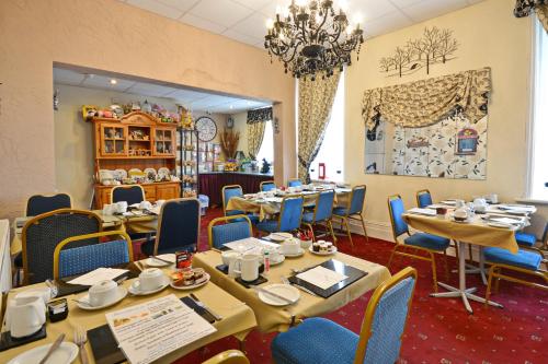 een eetkamer met tafels en stoelen en een kroonluchter bij The Derby Hotel in Blackpool