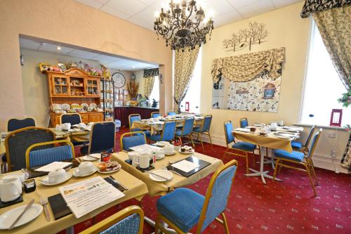 a dining room with tables and blue chairs at The Derby Hotel in Blackpool