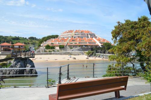 a bench in front of a beach with a building at Playa De Arnadal Isla in Isla