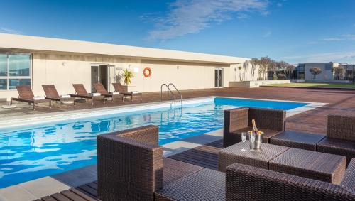 - une piscine avec des chaises en osier et une table dans l'établissement Lagoon Beach Hotel & Spa, au Cap