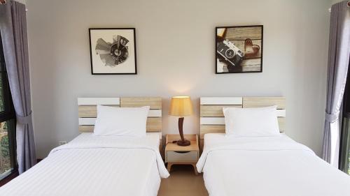 two beds in a room with white sheets at The Focus Khaoyai Resort in Mu Si